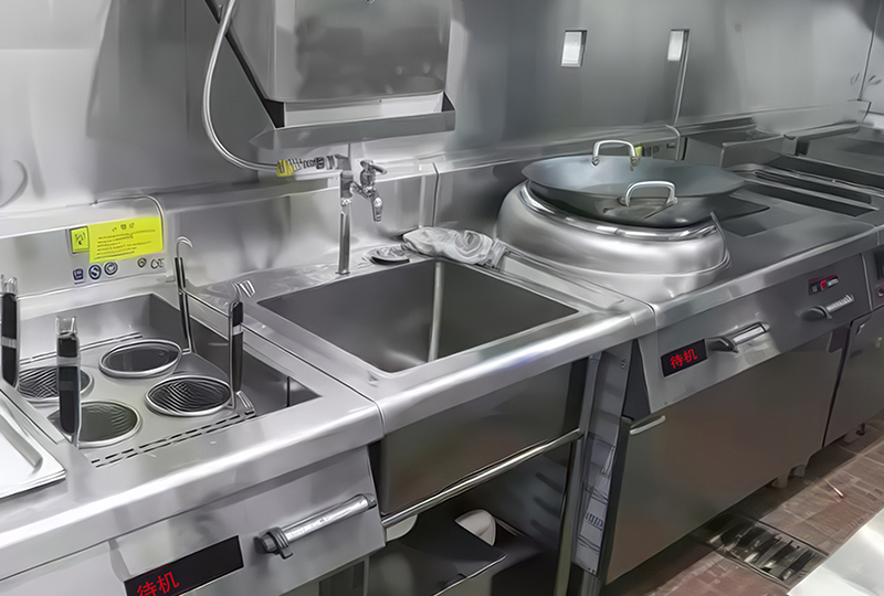 Image of a professional stainless steel kitchen with various cooking equipment, including a sink, stovetop, fryer, and a large cooking pot on an induction burner.