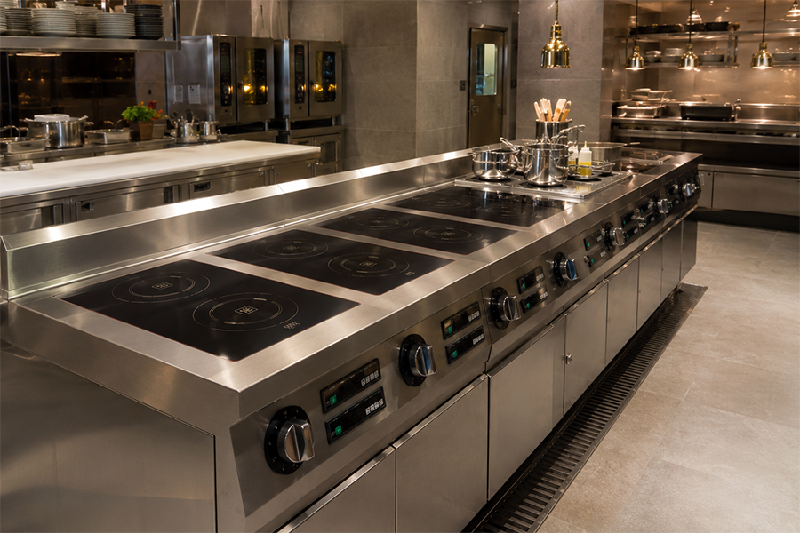 Commercial Induction Cooking vs Gas: Which Is Better for Restaurants? 2 High-end commercial induction cooking range installed in a luxury hotel kitchen, featuring multiple induction zones, stainless steel construction, integrated storage cabinets, and professional cookware in a modern foodservice environment.