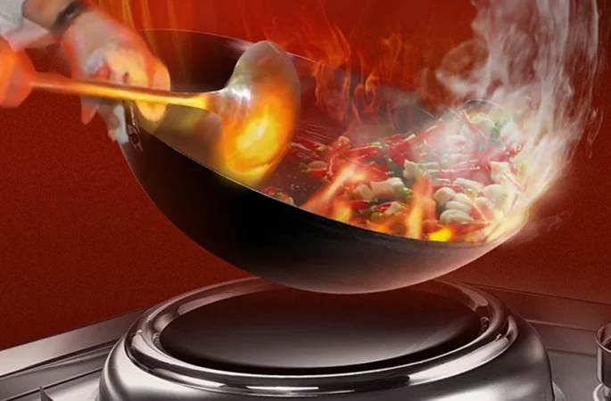 Dynamic cooking on a commercial Chinese induction wok with flames engulfing stir-fry.