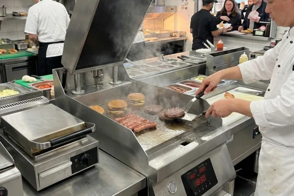Commercial clamshell griddle used in a professional restaurant kitchen for high-volume cooking
